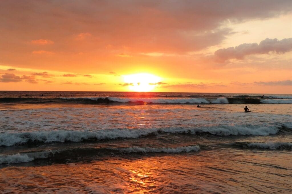 golden sunset on a beach with crashing waves with a surfer