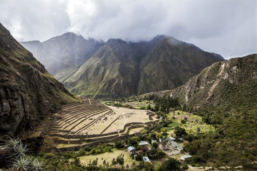 bird's-eye view of small Peruvian town in a lush valley surrounded by grassy terraces and alpine mountain ranges on the Salkantay Hidden Valley Trek