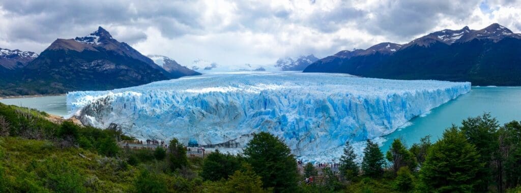 Large blue glacier sheet on a lake surrounded by mountains