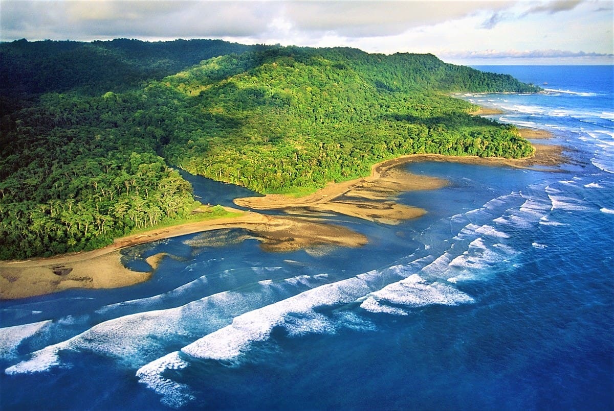 overhead shot of sandy beach between green mountains and blue ocean at Corcovado National Park